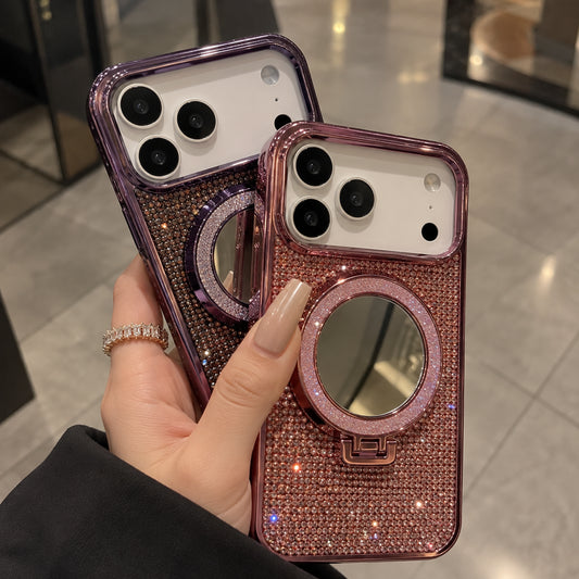 Two rhinestone-covered phone cases with circular mirror pockets are held in a hand. The case in the foreground is rose gold, and the case behind it is purple.