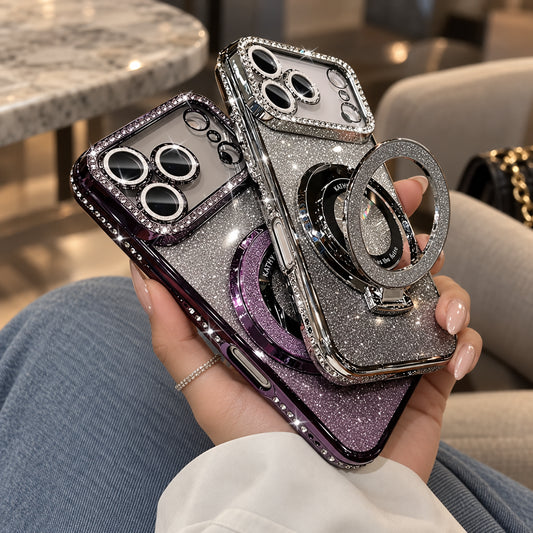 A hand holds two sparkling phone cases with camera protectors and built-in ring stands. The cases have glittery silver and purple finishes with rhinestone trim, shown in a casual indoor setting.