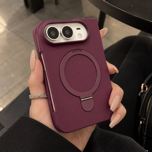 A person holds a dark purple magnetic phone case with a built-in kickstand. The case features a silver camera bezel and is shown being held by a hand with manicured nails and a ring.