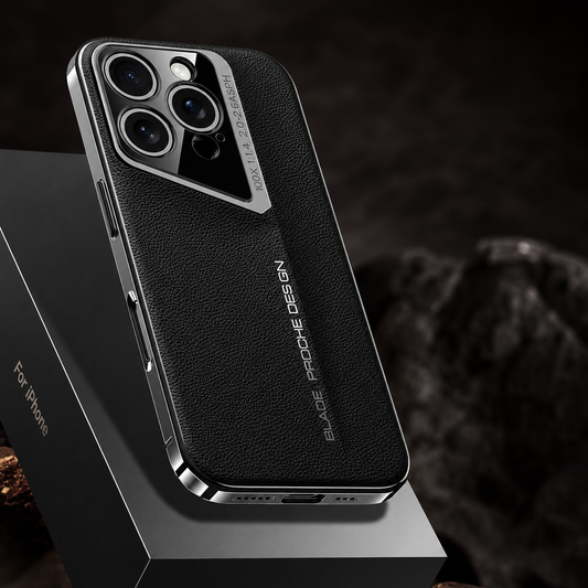 A black pebbled phone case rests on a dark angular platform beside rough rock, showing silver-colored trim and a slanted camera surround.