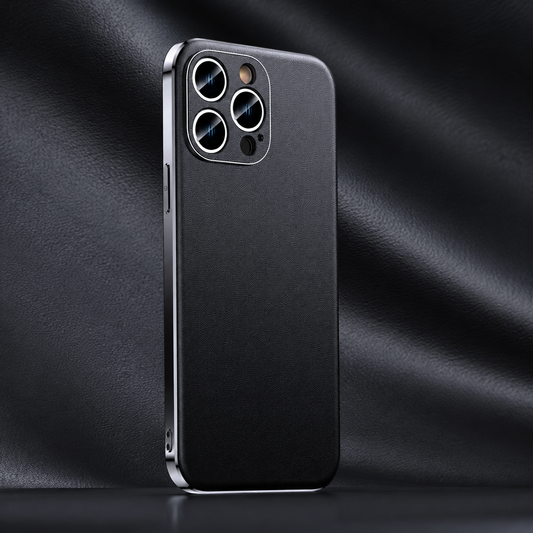 A black fine-textured phone case stands against folded black material, showing shiny silver-colored edges and a square camera surround with circular lens openings.
