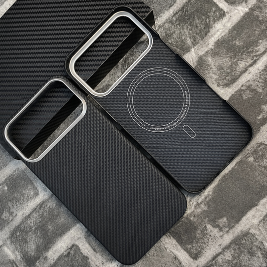 Two black woven phone cases lie on a gray brick-patterned surface beside a black textured box. One shows the outer back and the other an interior circular magnetic marking.