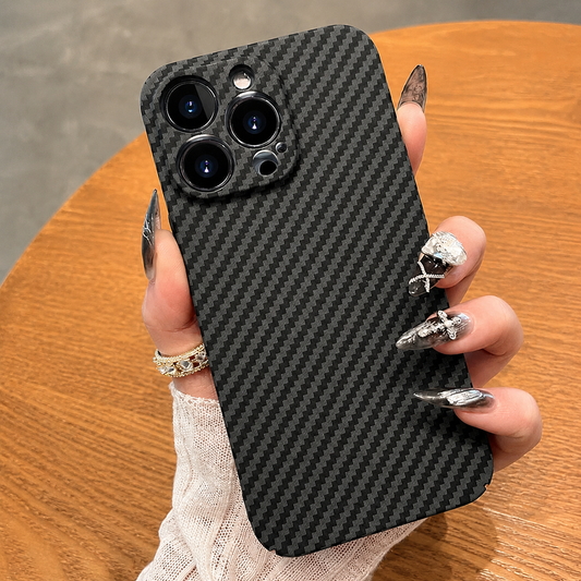 A hand holds a black diagonally patterned case above a round wooden table, with three camera lenses visible.
