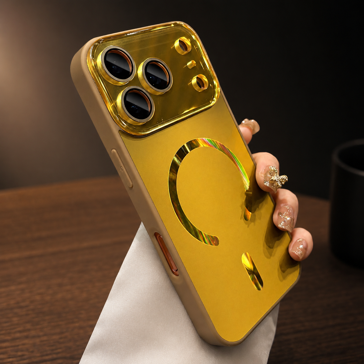 Hand holds a yellow case upright above a wooden table. Its reflective circular magnetic ring, alignment bar, and glossy matching camera panel catch warm light.