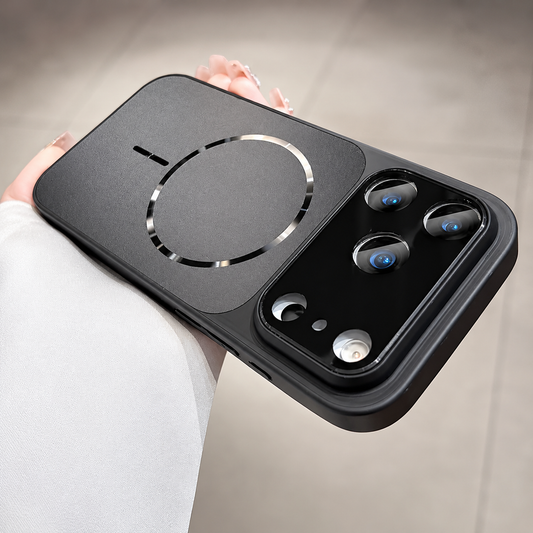 A hand holds a dark gray phone case horizontally over a tiled floor. A matte back panel has a segmented circular ring and bar, beneath a glossy wide three-lens camera panel.