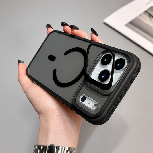 Hand holds a smoky transparent black case against a gray tabletop. A black magnetic ring sits below a raised camera frame, with a small silver oval inset alongside the cameras.