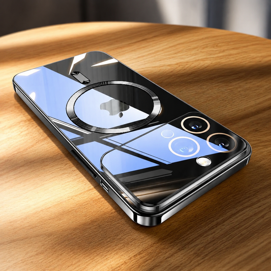 A highly reflective clear-backed phone case with dark silver edges lies diagonally on a wooden table. A circular magnetic marking surrounds the Apple logo, with a short bar below. Dark and blue window reflections cross the glossy surface and camera panel, while the side frame and charging cutouts remain visible.