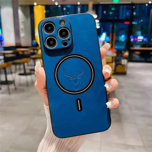 A hand holds a blue leather-look phone case upright in a café. A deer head is embossed inside the black circular rear ring beneath its matching three-camera panel.