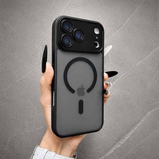 A hand holds a smoky gray frosted phone case upright against gray stone. Its black ring surrounds the visible Apple logo, with a short bar below and broad three-camera panel above.