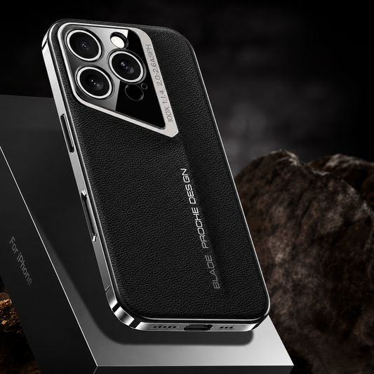 A black pebbled phone case rests on a dark angular platform beside rough rock, showing silver-colored edges and a slanted camera surround.