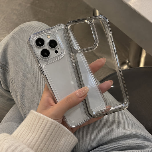 A clear, transparent phone case with a raised camera bumper is shown fitted on a white smartphone, held by a person wearing light gray sweatpants and a cream ribbed sweater.