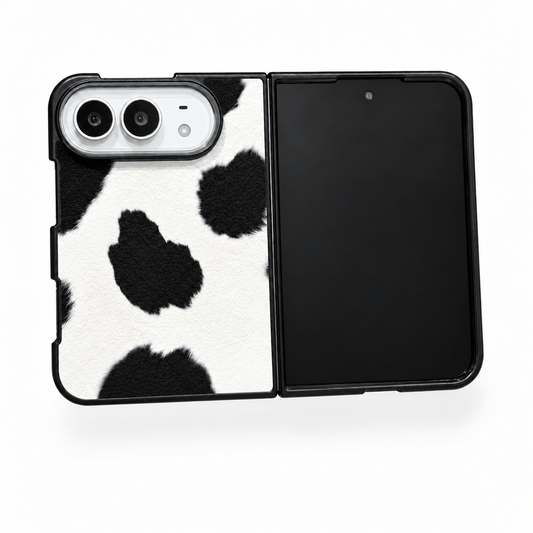 A black and white cow-print phone case shown open on a smartphone, with a solid black back panel on the right side, photographed on a clean white background.