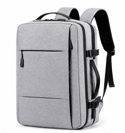 A light gray rectangular backpack stands at an angle with padded straps, top handle, front zipper pocket, side carry handle and black compression buckles.