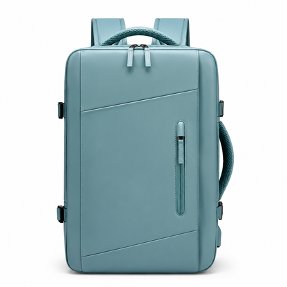 A muted blue rectangular backpack faces forward, showing diagonal front seams, a narrow vertical zip pocket, double main zipper, woven top and side handles and padded shoulder straps.
