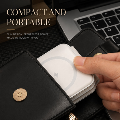 A hand slides a folded white square charger into the pocket of an open black wallet-style organizer beside a laptop keyboard. A pale circular charging ring marks the charger's face, and the organizer's flap has a gold-colored snap.