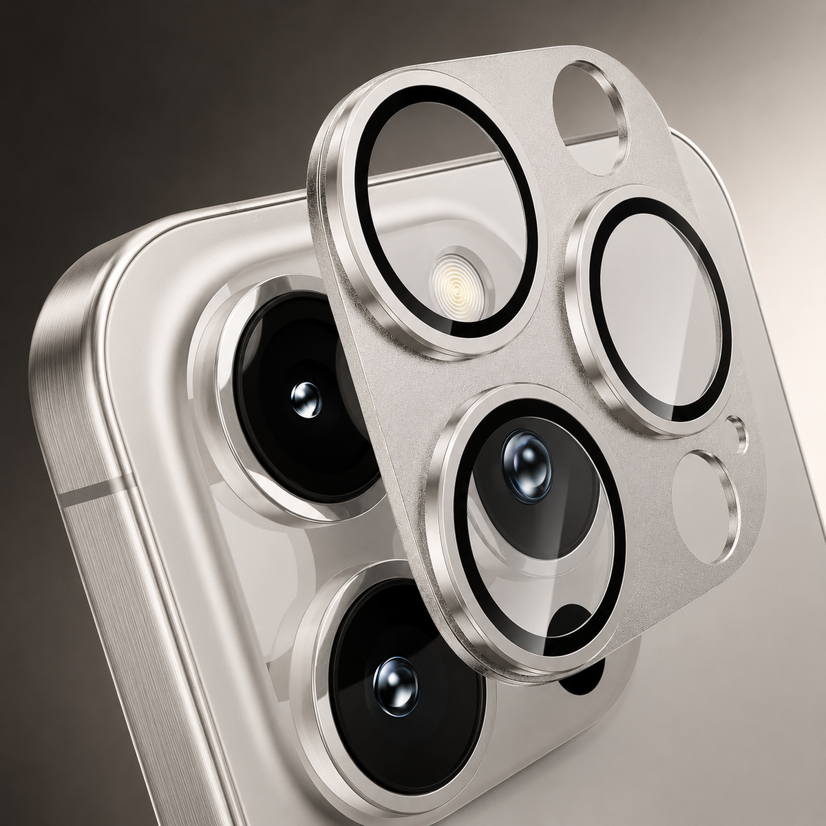 A silver-colored camera protector with three black-edged transparent lens rings floats close above a matching phone's camera cluster.