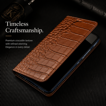 A tan wallet lies partly open above a phone with a dark screen on ribbed black material. Its broad textured scales, narrow fold and stitched rim are visible. Text reads Timeless Craftsmanship.