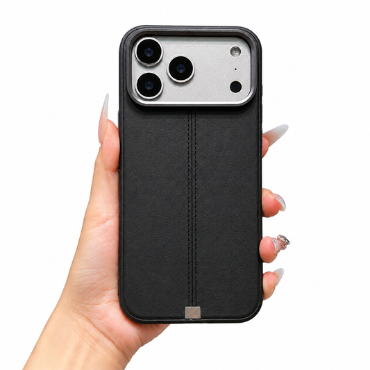 A hand holds a black leather-look case upright on white. A vertical double-stitched seam ends in a small silver-colored tab beneath the broad pale camera panel.