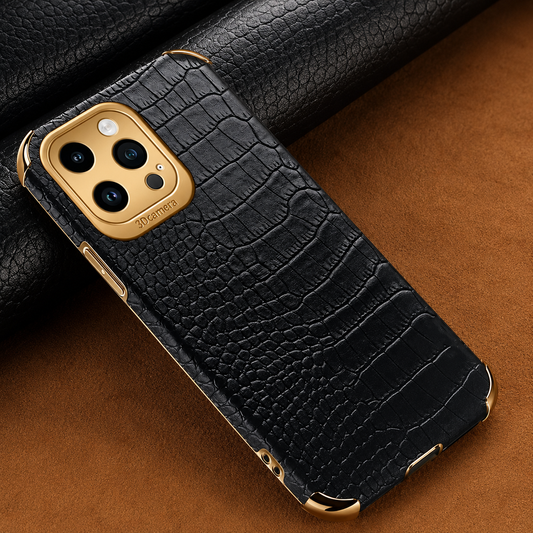 Black crocodile-pattern case lying on a brown surface beside rolls of matching textured material, with gold-colored corners and camera trim.