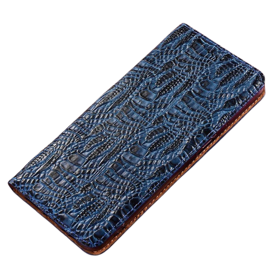A closed blue crocodile-pattern wallet phone case lies diagonally on white, showing glossy raised scales and brown edging around the sides.