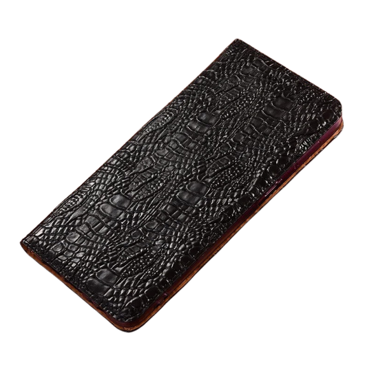 A closed black crocodile-pattern wallet phone case lies diagonally on white. Glossy raised scales cover the flap, with brown edging visible around the sides.
