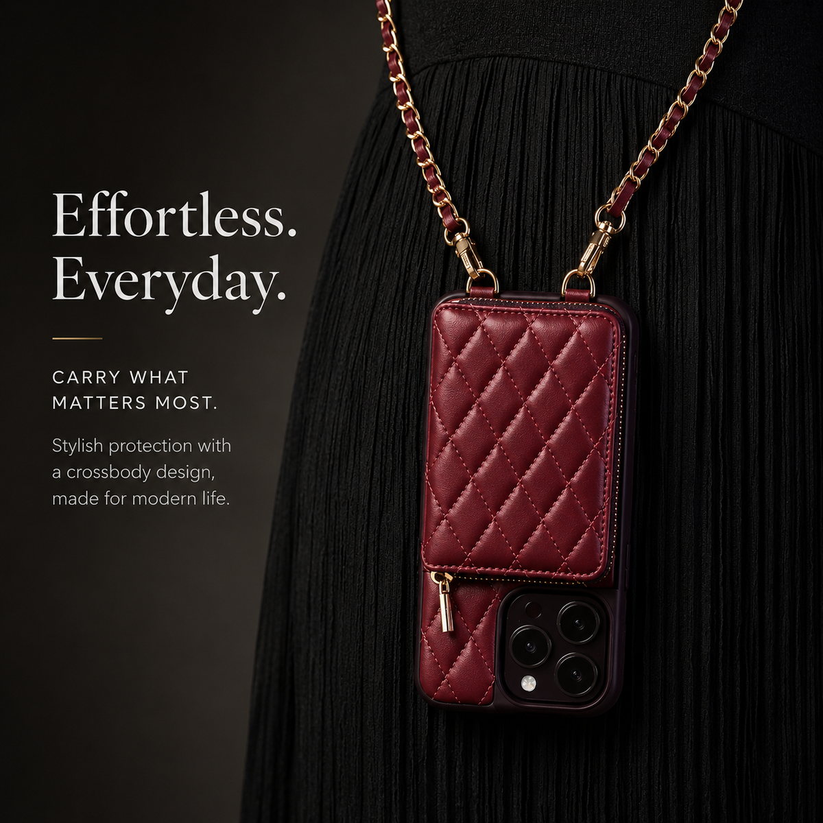 Burgundy quilted phone wallet hangs vertically from a gold-colored woven chain against a black pleated dress. The zippered pocket sits above the exposed camera lenses.