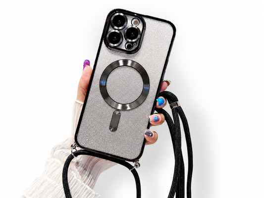 A hand with multicolored nails holds a silver glitter case edged in black. A metallic circular magnetic design sits on the back, with a matching black cord strap attached at the bottom.