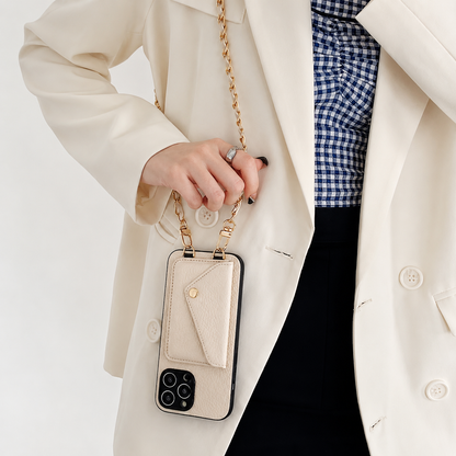 A woman in a cream blazer holds the chain of a cream phone wallet hanging vertically. A gold-colored snap fastens its envelope-shaped rear pocket.