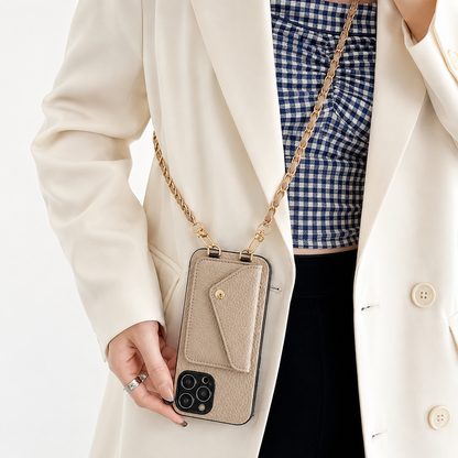Taupe pebbled phone wallet hangs vertically from a gold-colored chain against a cream blazer. Its envelope-shaped rear pocket sits above the exposed cameras.
