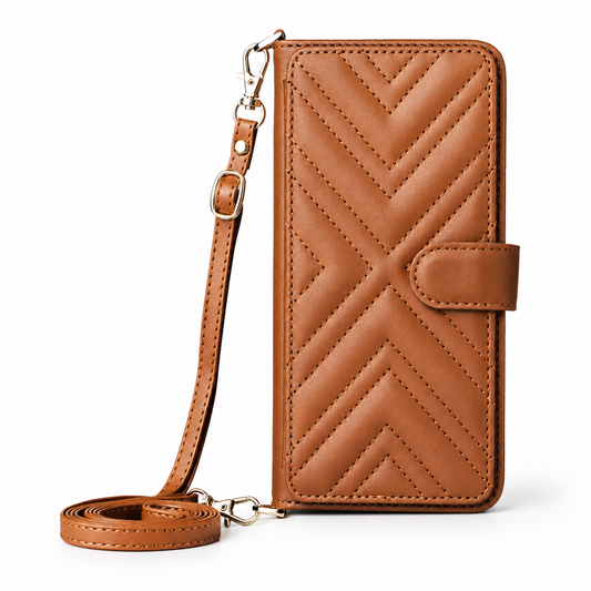 A closed brown leather-look wallet phone case stands upright beside its matching adjustable strap. Chevron stitching crosses the front, and gold-colored clips attach the strap.