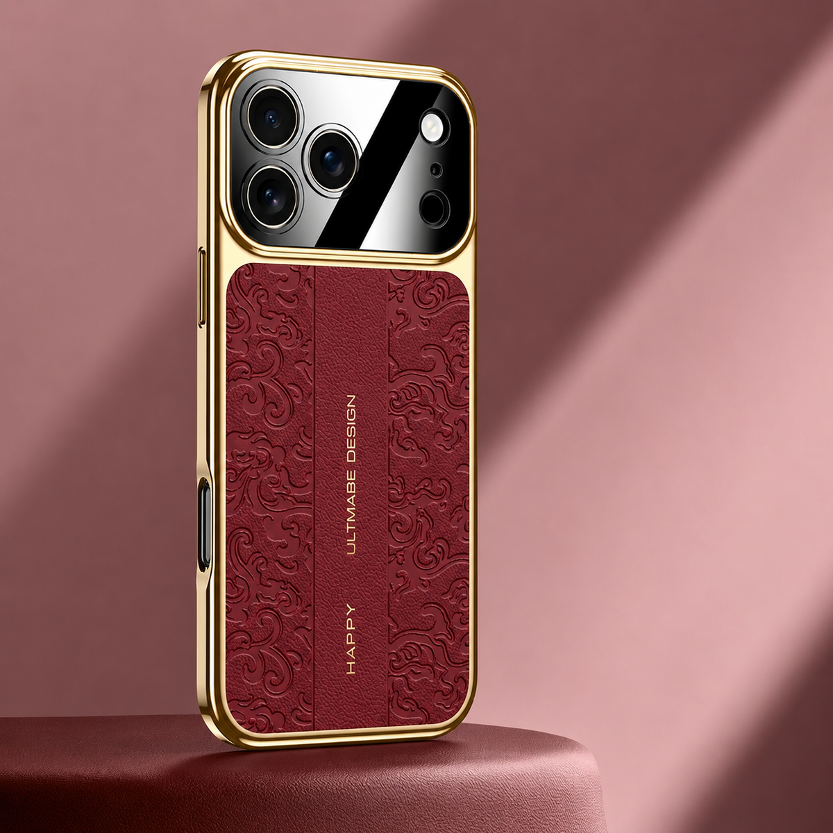 A burgundy embossed case stands on a red pedestal, bordered by gold-colored edges. Its curling motifs surround a plain central strip beneath the mirrored camera panel.