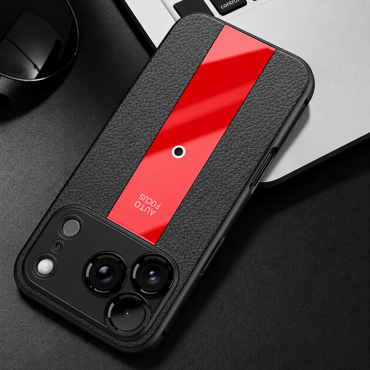 Black textured case with a glossy red center stripe lies beside a laptop on a dark desk. The wide camera panel has separate round lens borders.
