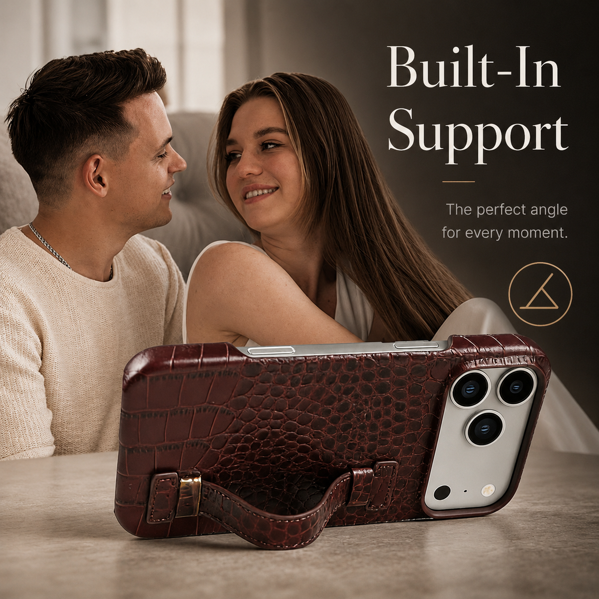 A brown textured case supports a phone horizontally using its curved back strap as a stand. Two people sit smiling at one another behind it.