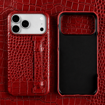 A red crocodile-style case stands beside its empty black-lined shell on red patterned material. The matching back strap lies flat against the raised texture.