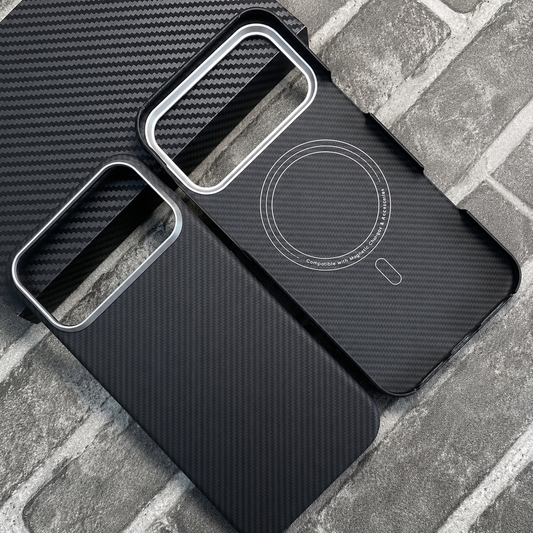 Two black woven phone cases lie on gray brick and a black textured mat. One shows its diagonal patterned back, and the other shows circular magnetic markings inside.