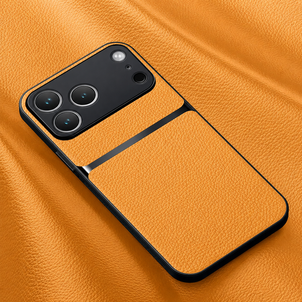 A yellow-orange pebbled leather-look phone case lies on matching material, with black edges, a glossy stripe and broad black camera panel.