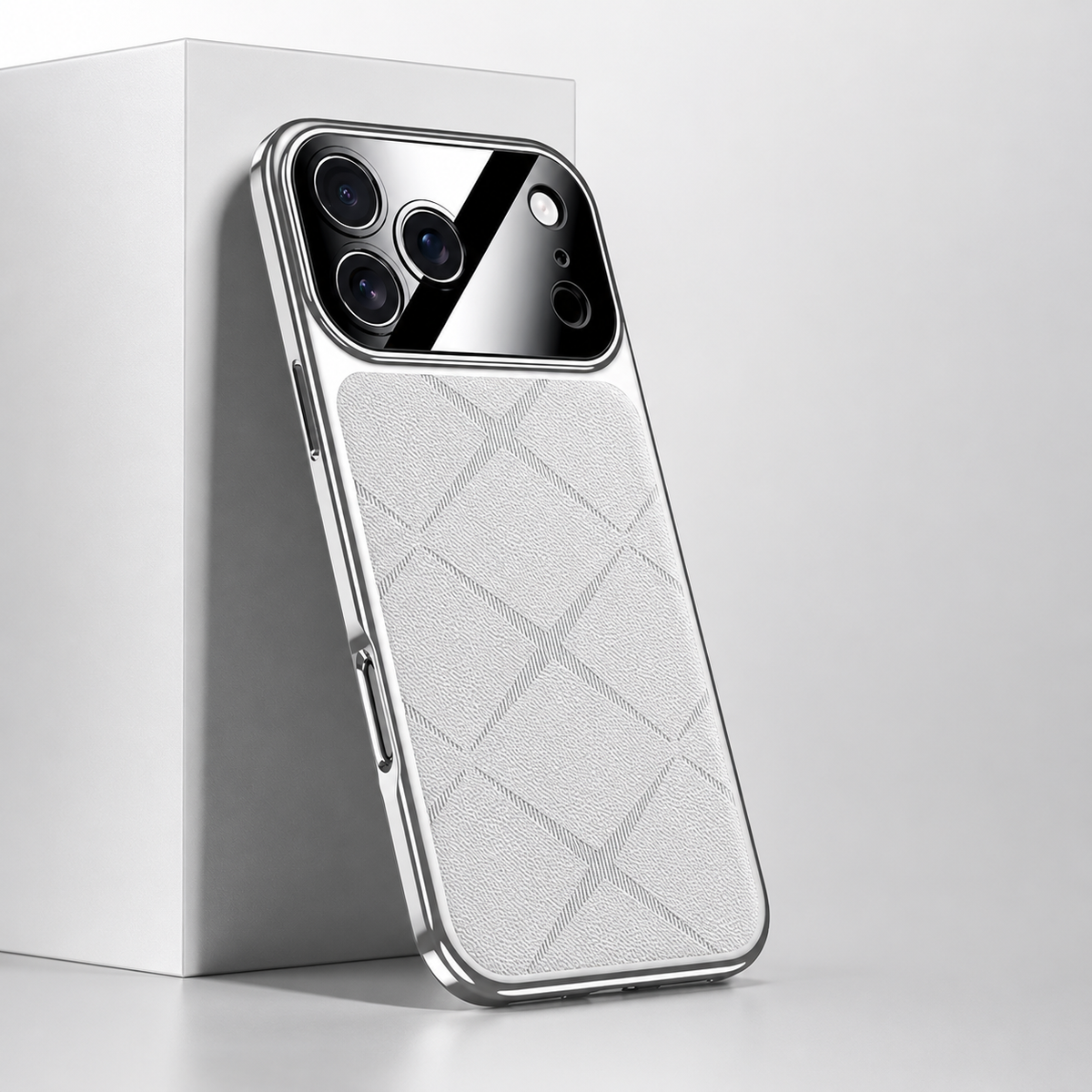 White diamond-pattern phone case leaning against a white block, with silver-colored edging and a glossy camera panel.