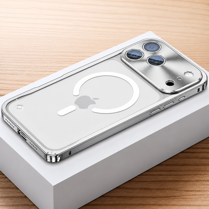 Silver-colored framed case lies face down on a white box, showing a frosted transparent back with a white broken magnetic ring and alignment bar. A broad reflective camera panel surrounds three lenses.