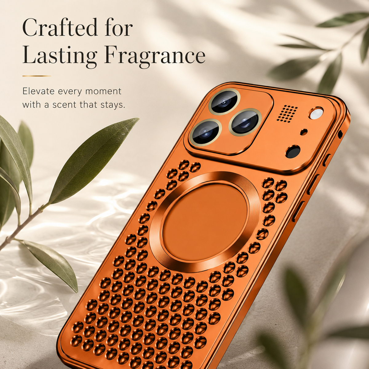 An orange perforated case rests among pale green leaves beneath Crafted for Lasting Fragrance.