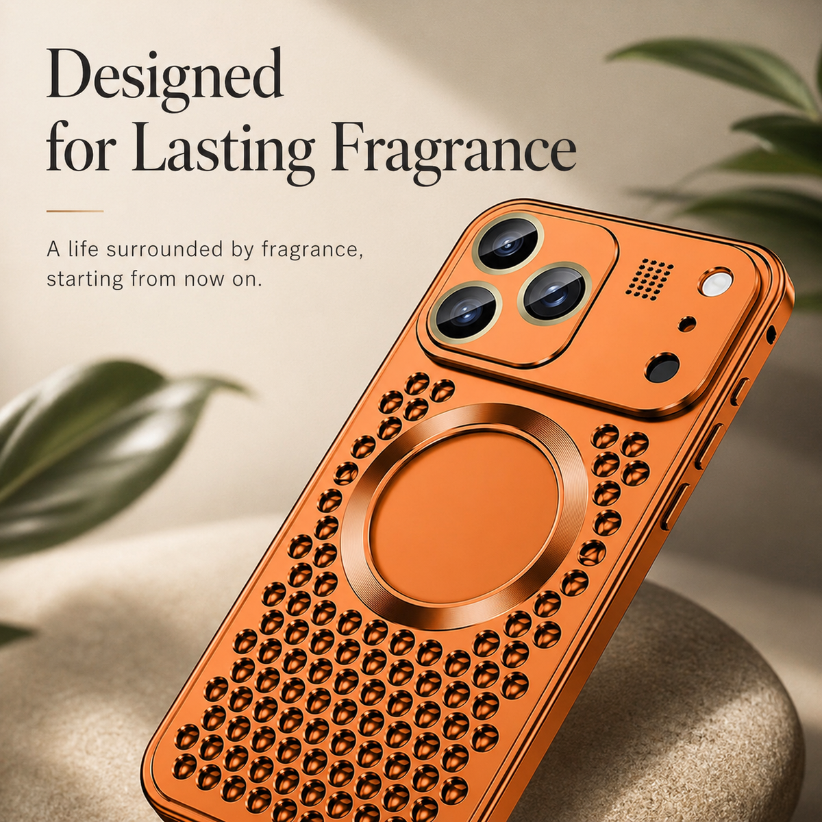An orange perforated case rests diagonally near green leaves beneath Designed for Lasting Fragrance.