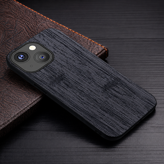 A black wood-grain-patterned case rests diagonally across a brown textured notebook on a dark wooden surface.