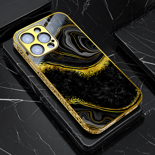 A gold-edged case lies on stacked black marble slabs, showing black and gray flowing bands bordered by gold-colored speckles.