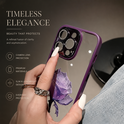 A hand with rings holds a pale reflective purple-edged case decorated with a purple rose. Decorative rings outline its camera openings.
