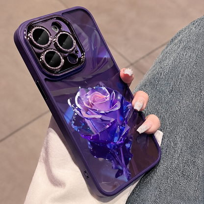 A hand holds a purple case beside blue jeans, decorated with a large purple faceted rose and matching leaves.