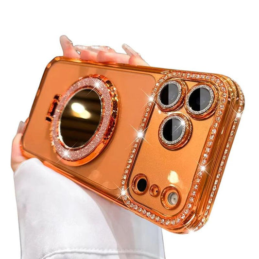 A hand holds an orange reflective phone case horizontally against white. Rhinestone-like trim surrounds the edges, camera openings and a large circular mirror ring on the back.