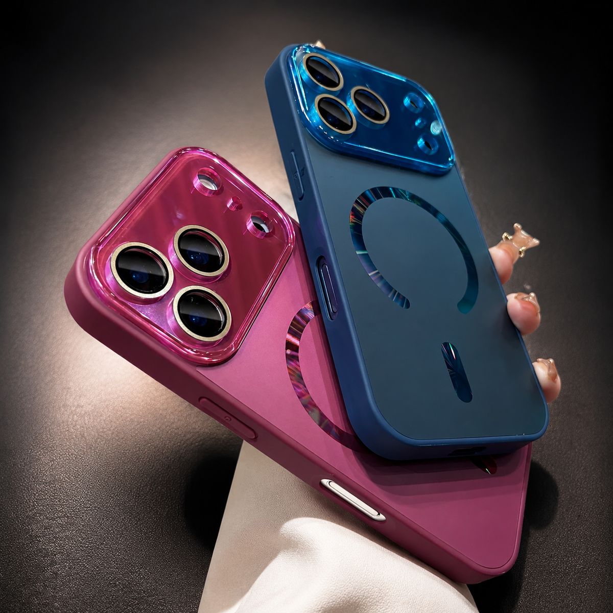 Blue and pink cases overlap in a hand, with reflective magnetic rings and matching glossy camera panels above their smooth backs.