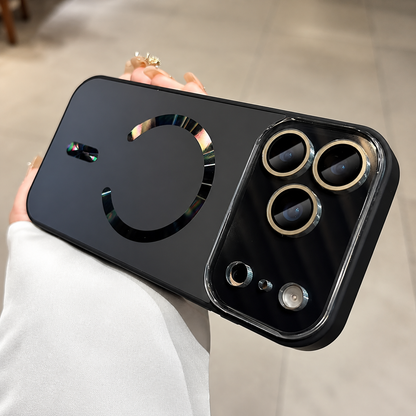 Hand holds a black case horizontally indoors. Its dark back has a reflective rainbow-tinted magnetic ring, alignment bar, and gold-colored camera lens surrounds.