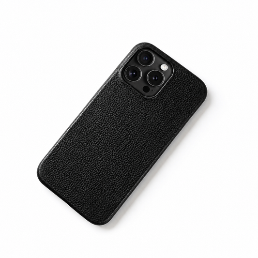 A black pebbled leather-look phone case lies diagonally against white, with a small square three-camera opening and softly rounded edges.