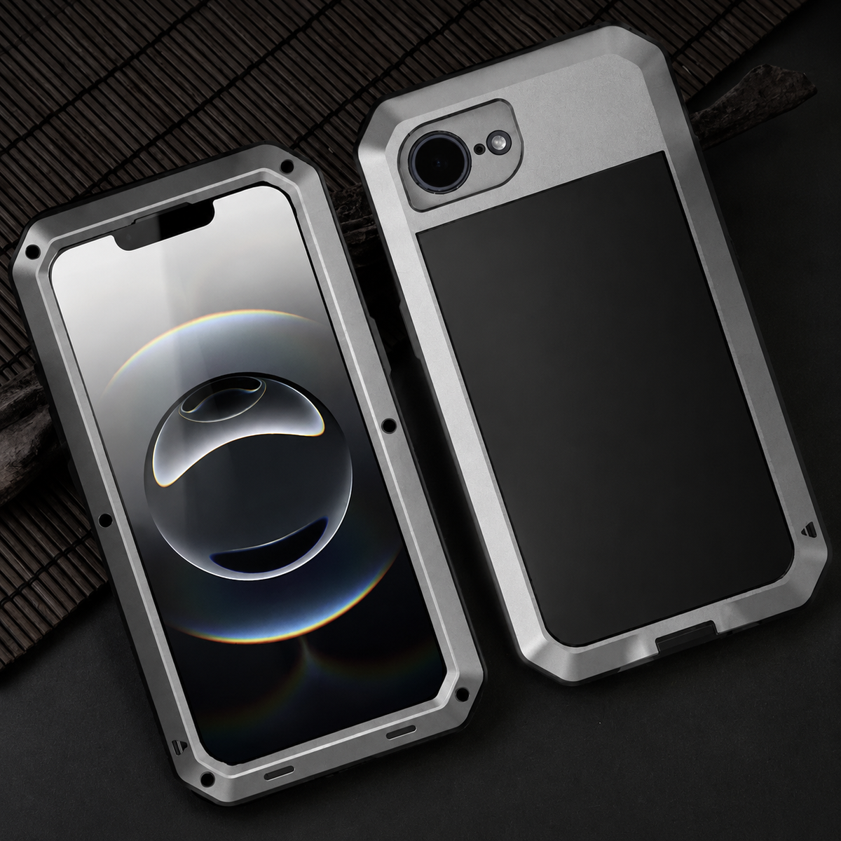 Front and rear views show a silver rugged case lying on dark ribbed fabric. The rear has a single large lens opening, while the front displays pale circular graphics.