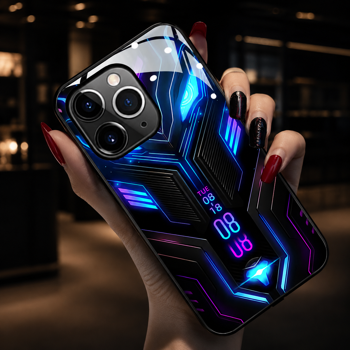 A hand holds a blue-and-purple circuit-patterned case close to the camera in a warmly lit interior.